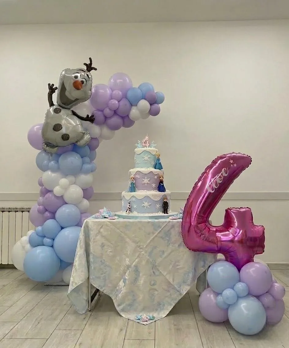 Tavolo della torta a tema Frozen con colonna di palloncini lilla e azzurri, pupazzo di neve in mylar e numero 4 fucsia stampato col nome