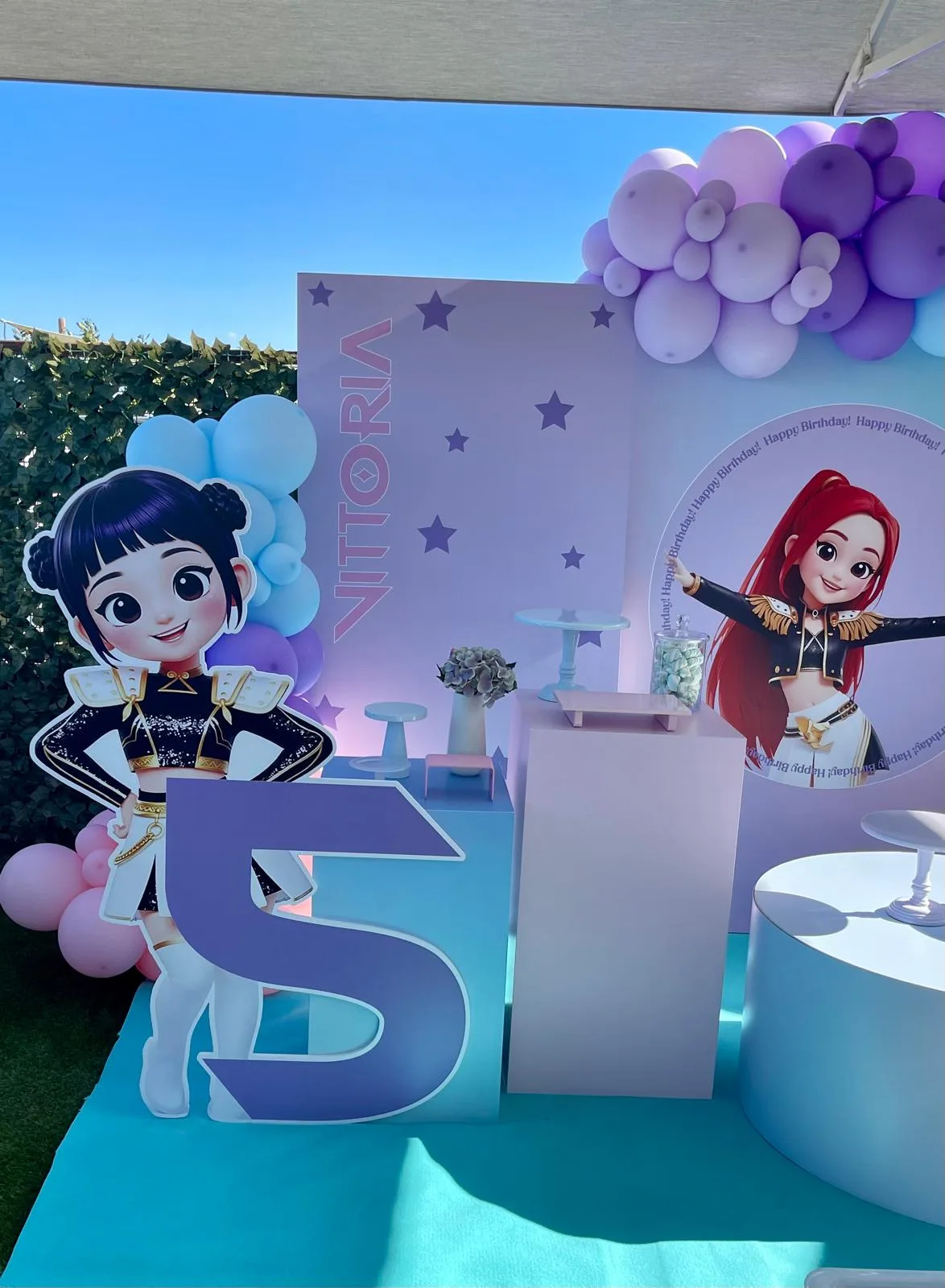 Pannello lilla con il nome Vittoria e le stelle, numero 5 sagomato, colonnine per i dolci e ghirlanda di palloncini viola, allestito in terrazza