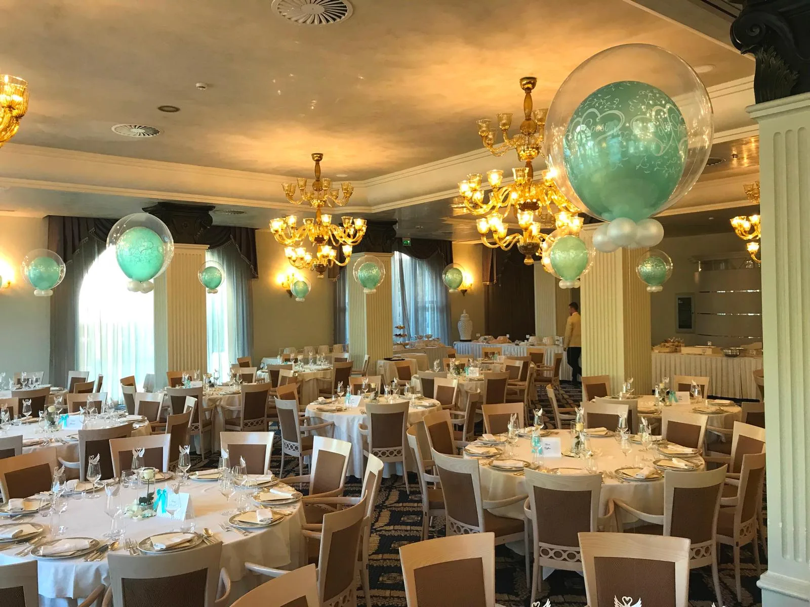 Sala del ricevimento con bubble trasparenti stampate e palloncini verde tiffany sospesi sopra i tavoli apparecchiati