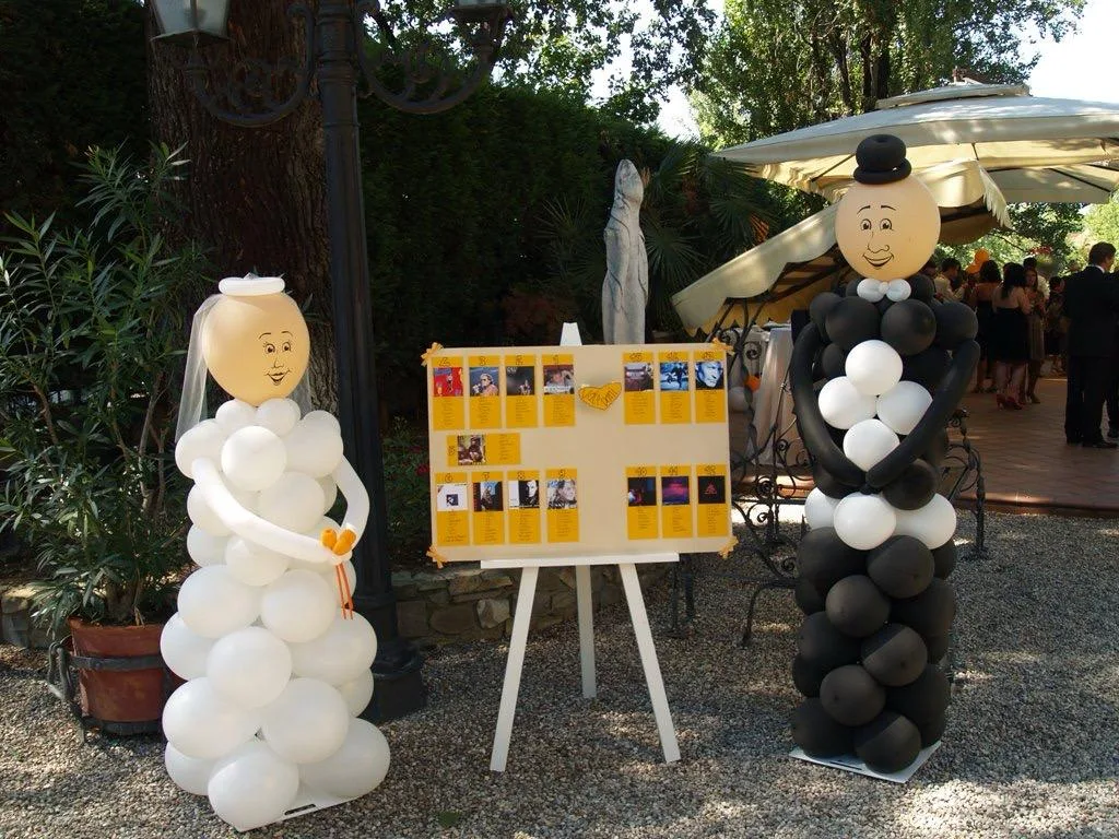 Tableau de mariage affiancato da due sculture di palloncini a figura intera che raffigurano la sposa in bianco e lo sposo in nero