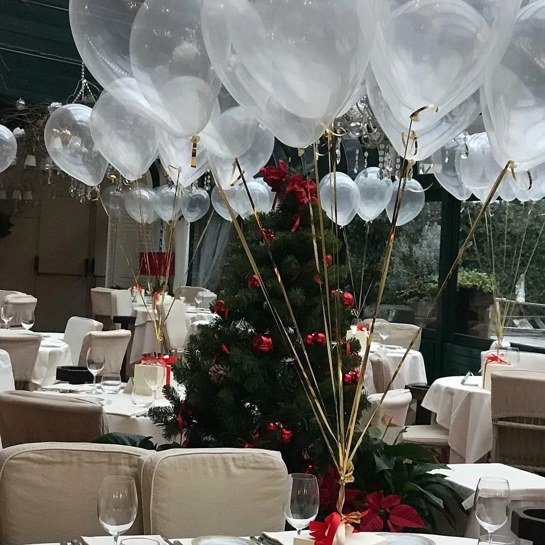 Bubble trasparenti a elio con nastri dorati che riempiono il soffitto della sala sopra i tavoli, in un ricevimento invernale