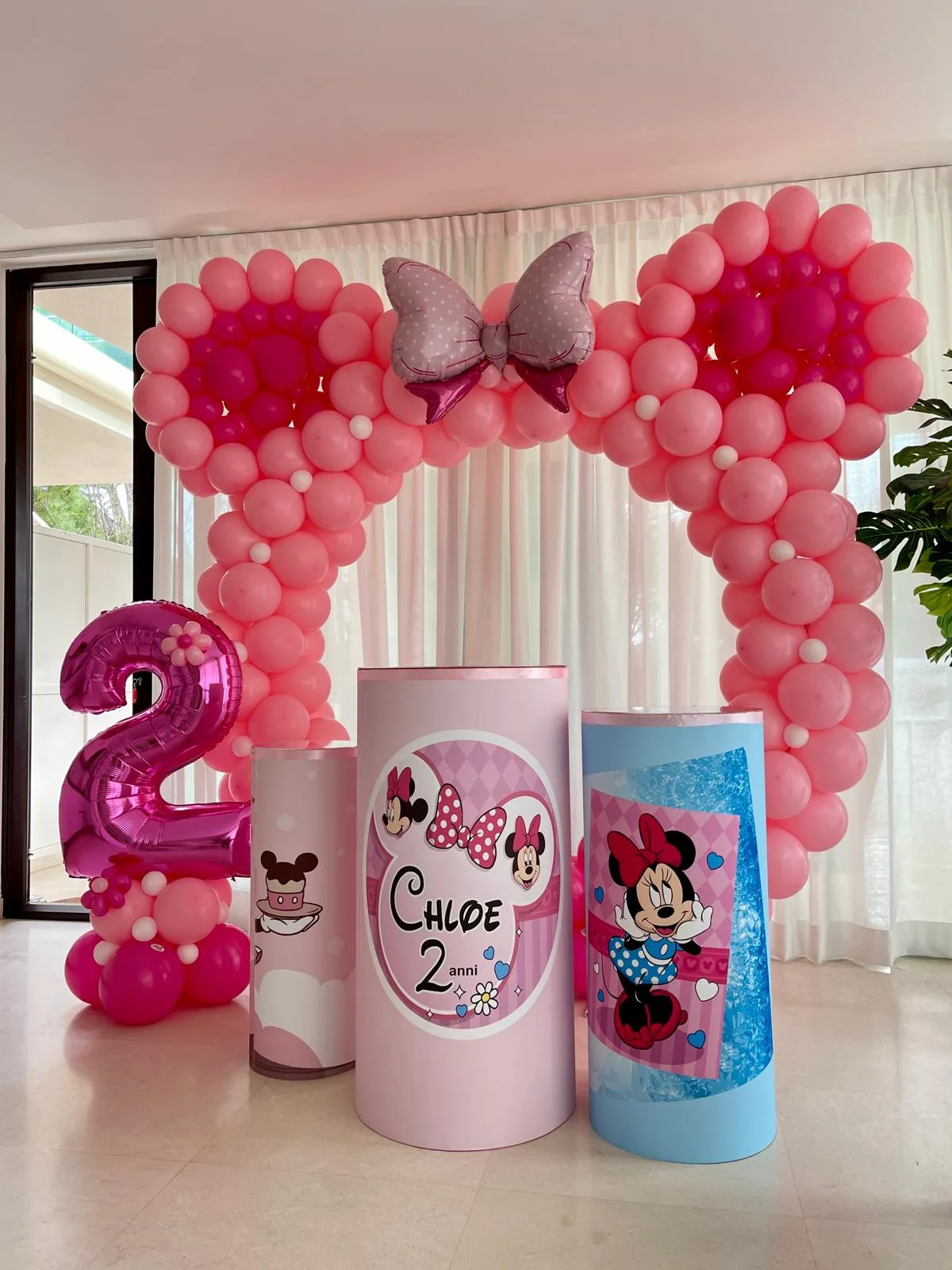 Arco di palloncini a forma di orecchie con fiocco, cilindri stampati con il nome Chloe e il numero 2, allestimento a tema Minnie in salotto
