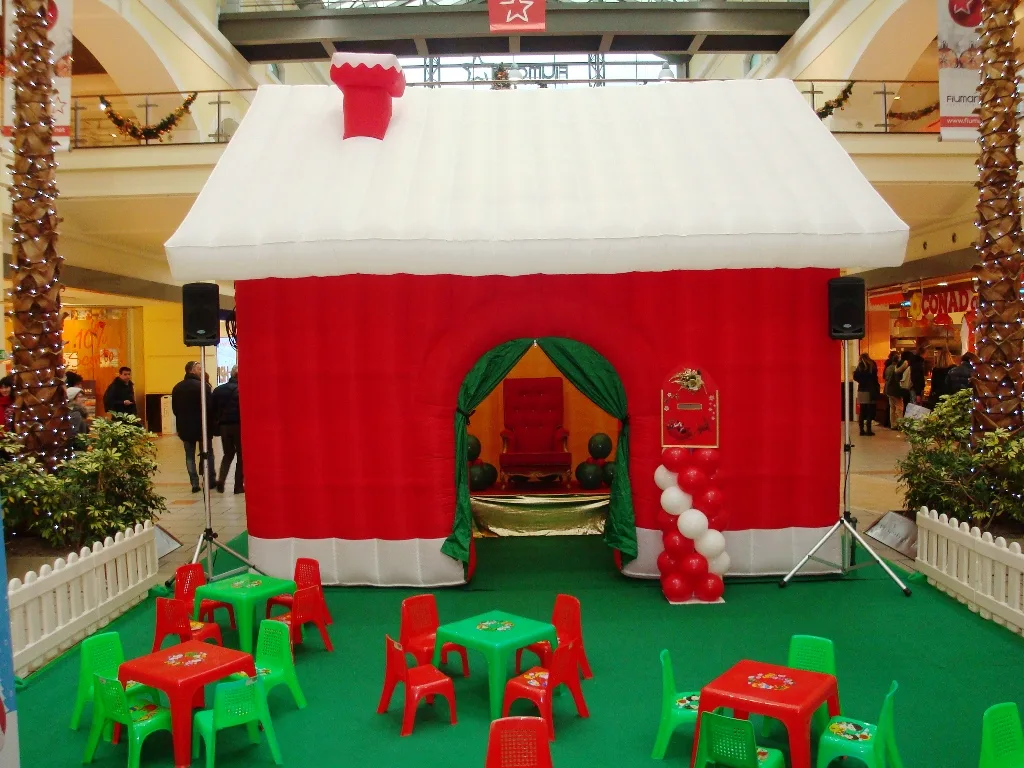 Interno della casetta gonfiabile natalizia con la poltrona rossa di Babbo Natale e le colonne di palloncini