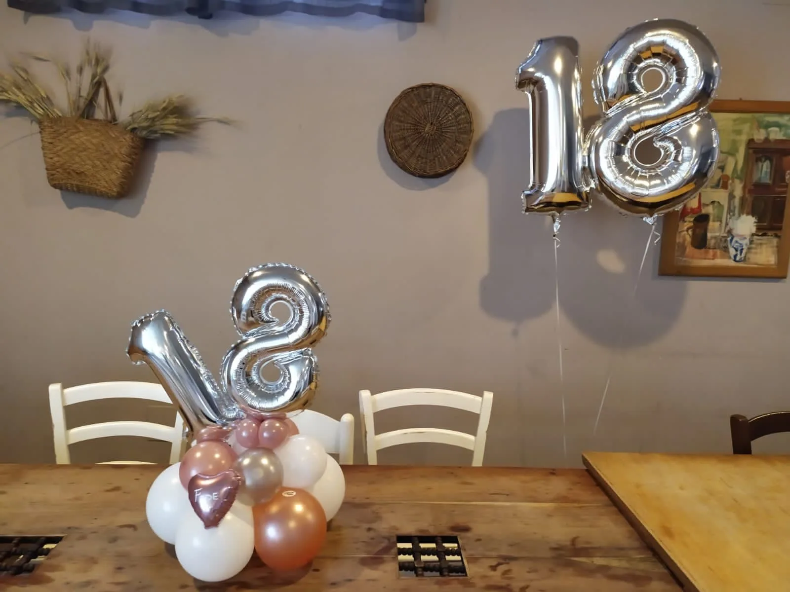 Composizione da tavolo con numero 18 in mylar argento, palloncini rosa antico, bianchi e rame e cuore stampato, con un secondo 18 a elio appeso alla parete