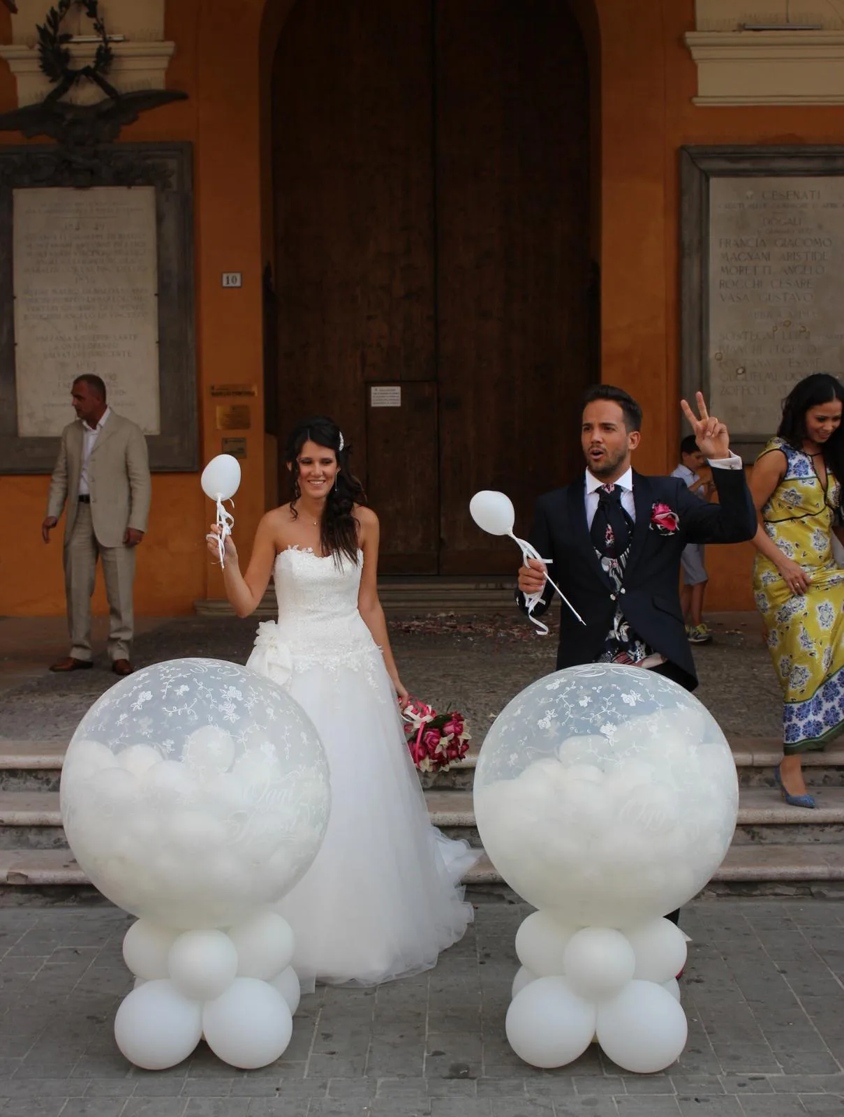 Sposi all'uscita del municipio fra due grandi sfere trasparenti stampate Just Married, riempite di palloncini bianchi e poggiate su basi di palloncini