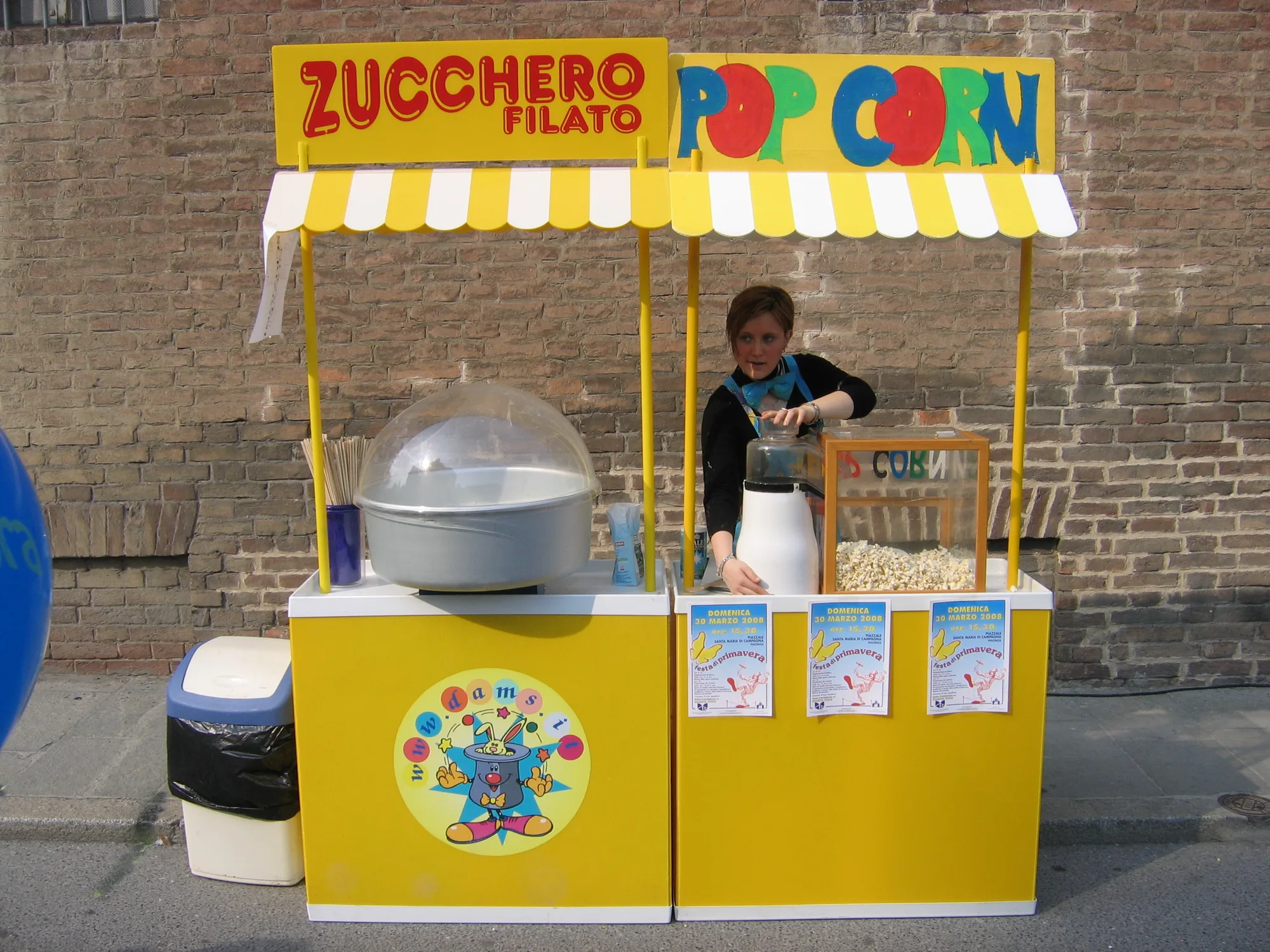 Carrettini gialli dello zucchero filato e dei popcorn montati in strada, con l'operatrice che prepara i popcorn