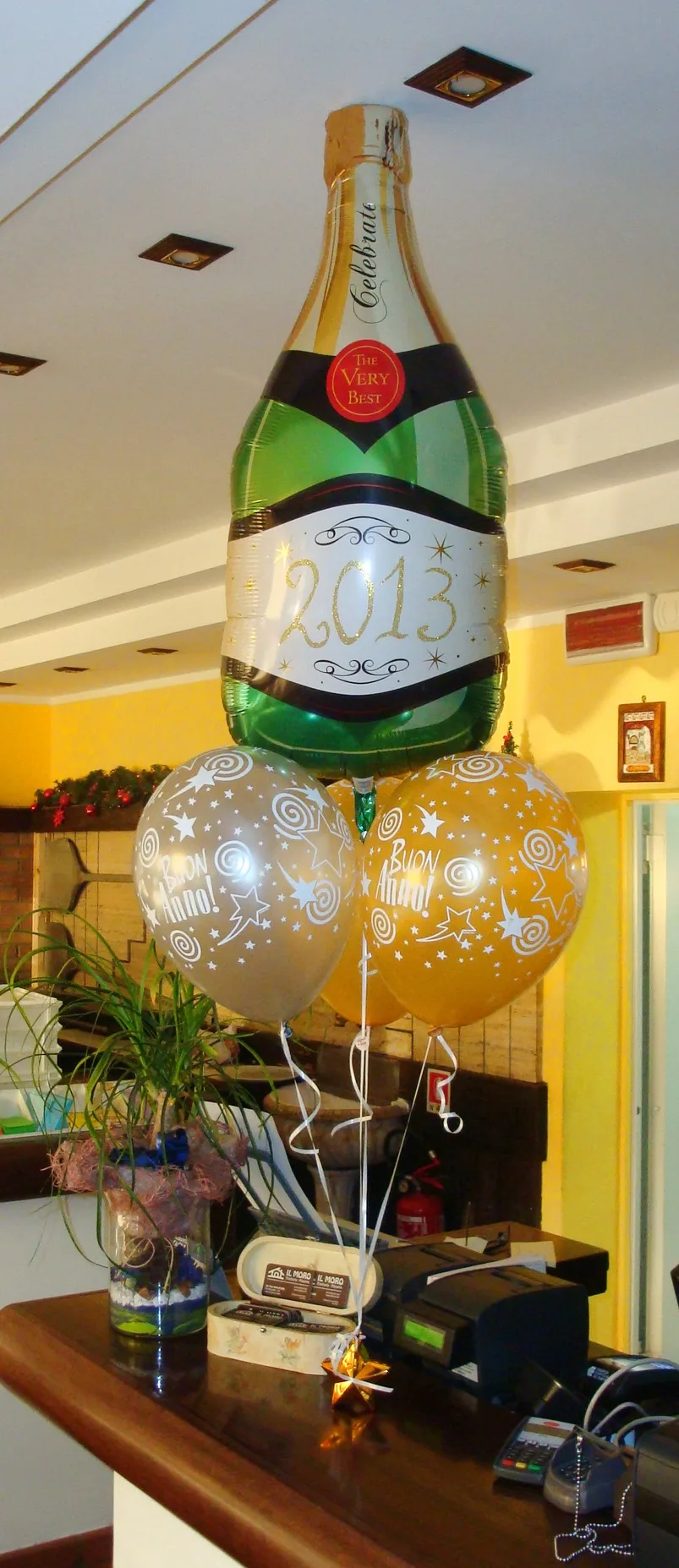 Bouquet su un bancone: palloncino a forma di bottiglia di spumante con la scritta 2013 e palloncini argento e oro con la scritta Buon Anno