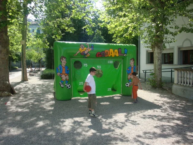 Due bambini con il pallone davanti alla porta gonfiabile Gooaal montata in un viale alberato