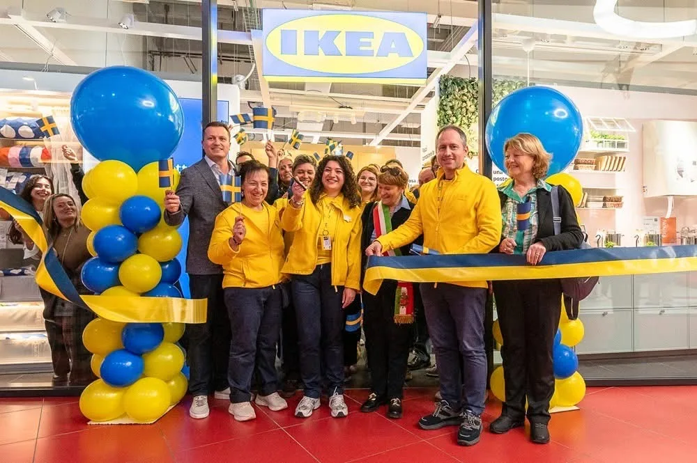 Taglio del nastro giallo e blu all'apertura di un grande negozio, con due colonne di palloncini gialli e blu sormontate da sfere giganti ai lati dell'ingresso