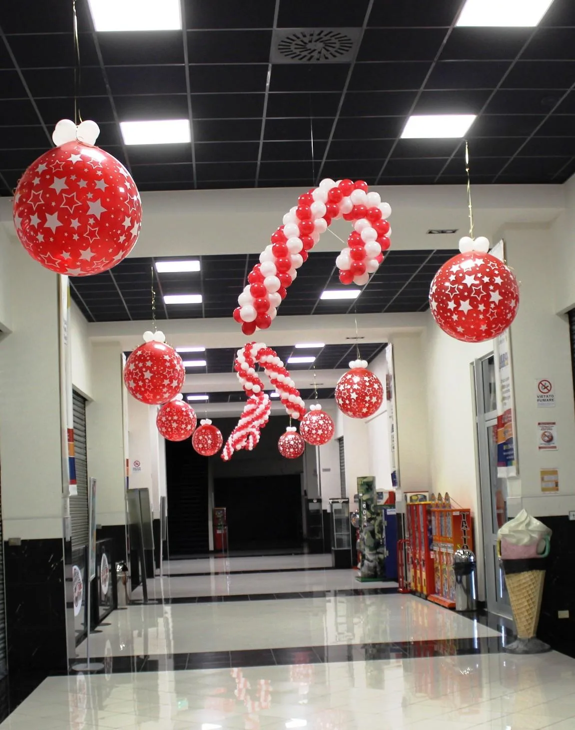 Bastoncini di zucchero di palloncini rossi e bianchi e palline rosse con le stelle appesi al soffitto di una galleria commerciale