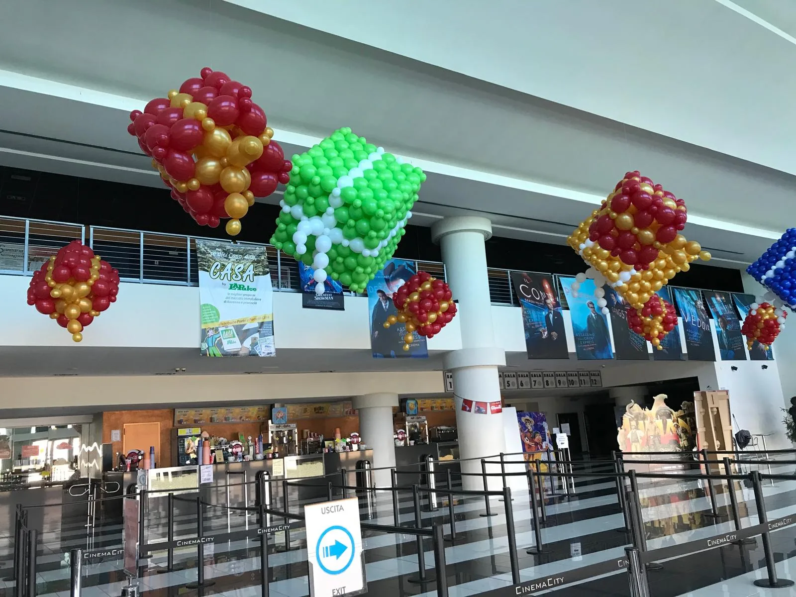 Pacchi regalo e decorazioni di palloncini rossi, oro, verdi e bianchi appesi nell'atrio di un cinema