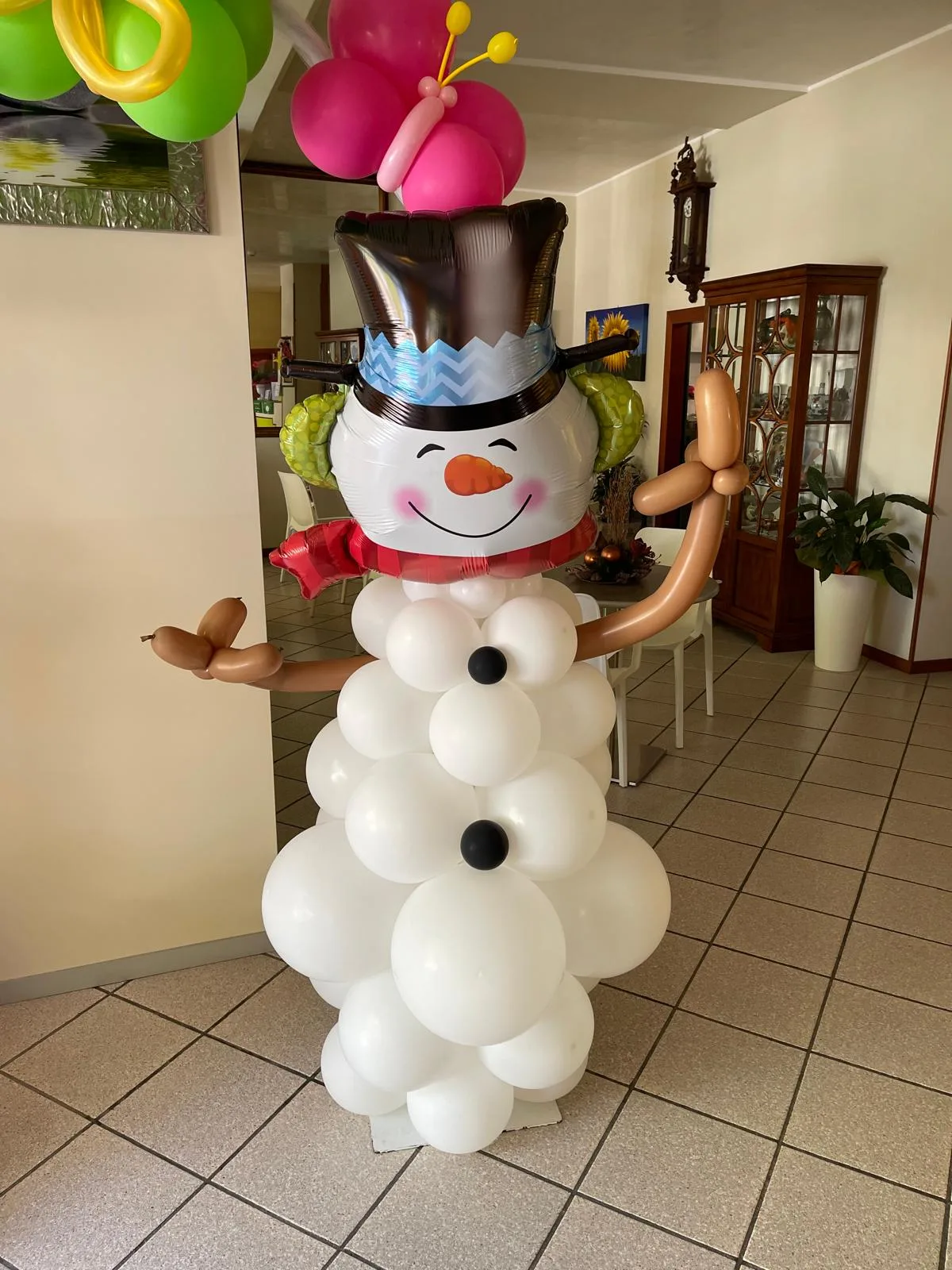 Pupazzo di neve di palloncini bianchi con la testa in mylar, il cilindro e le braccia di palloncini marroni, nella sala di un hotel