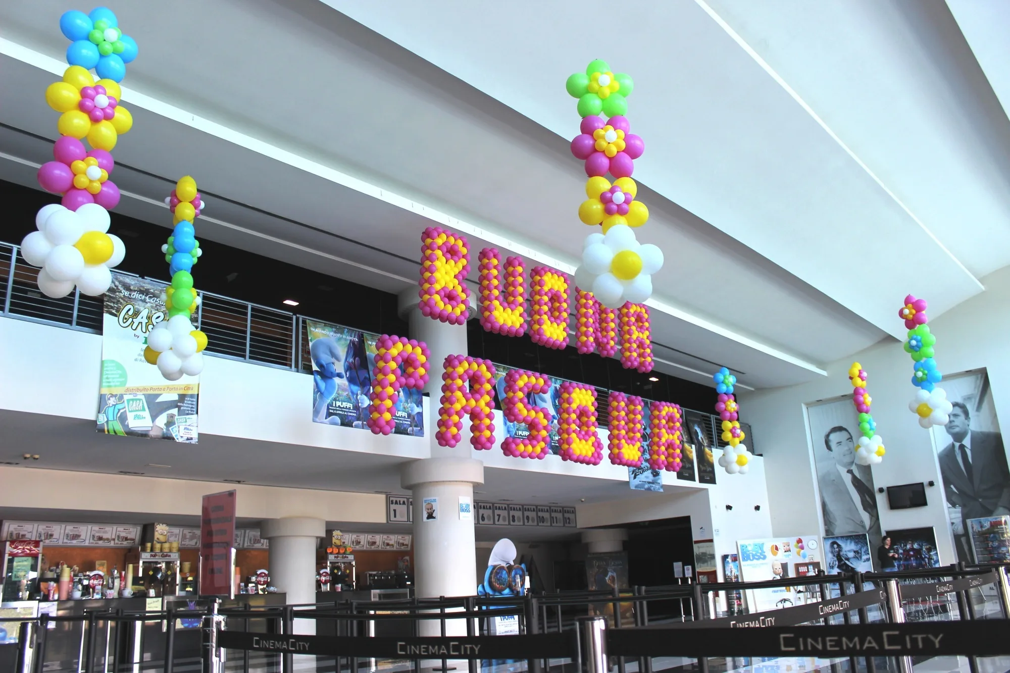 Scritta Buona Pasqua fatta di palloncini fucsia e gialli e catene di fiori di palloncini appese nell'atrio di un cinema