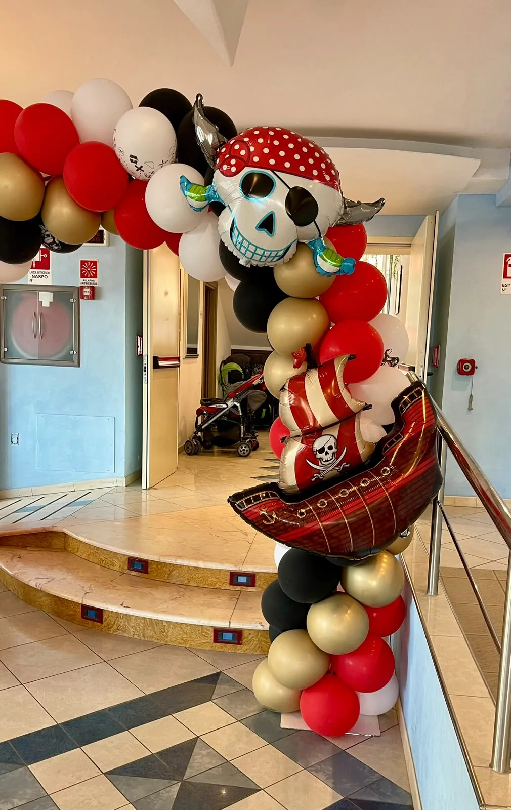 Dettaglio dell'arco dei pirati: il teschio con la bandana a pois e il veliero in mylar sulla colonna di palloncini rossi, neri e oro