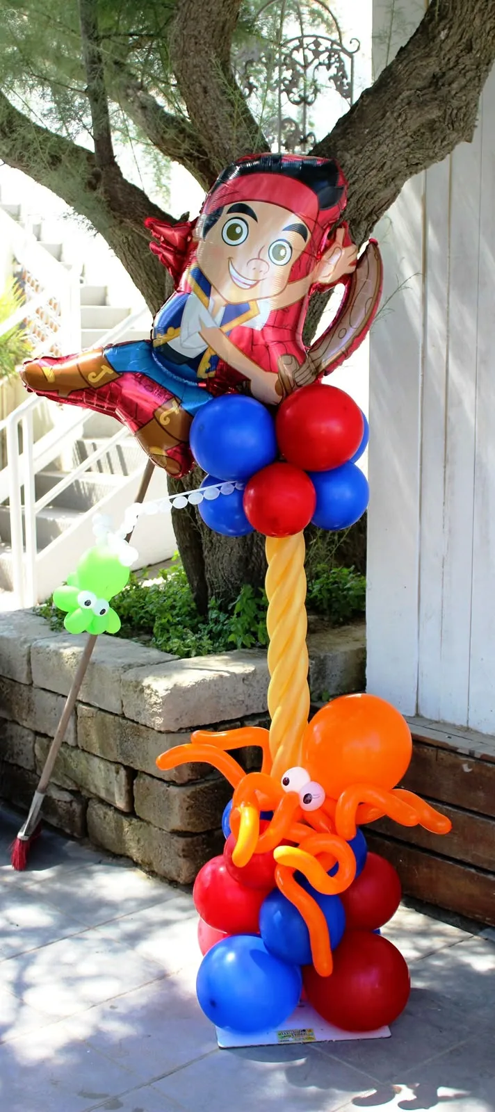 Colonna di palloncini rossi e blu con un piccolo pirata in mylar in cima e un polpo arancione di palloncini alla base, all'aperto