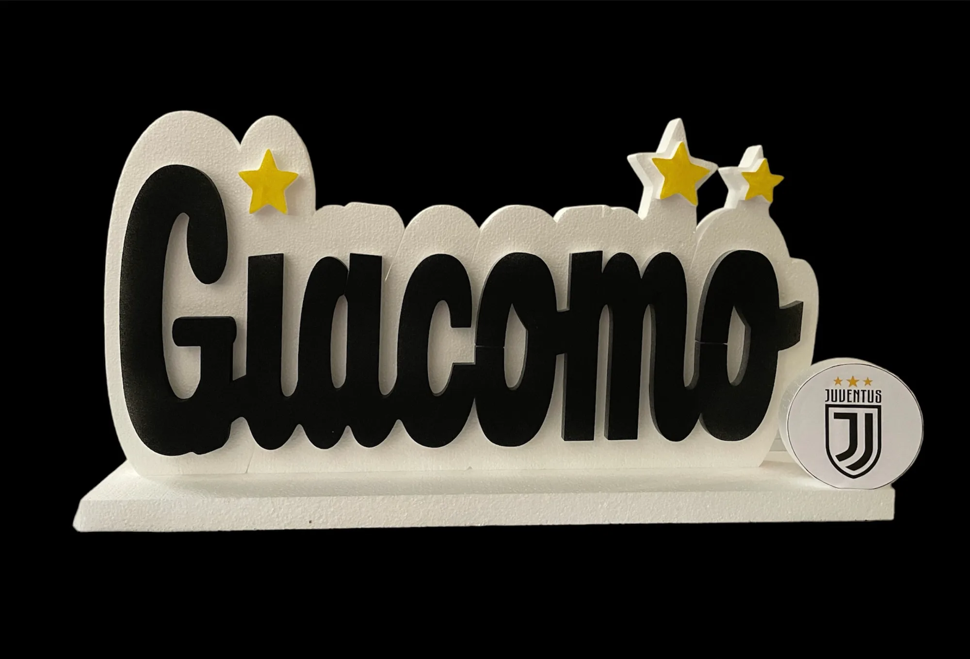 Nome Giacomo in lettere di polistirolo nere su sagoma bianca, con stelle gialle e un tondo con lo stemma di una squadra di calcio