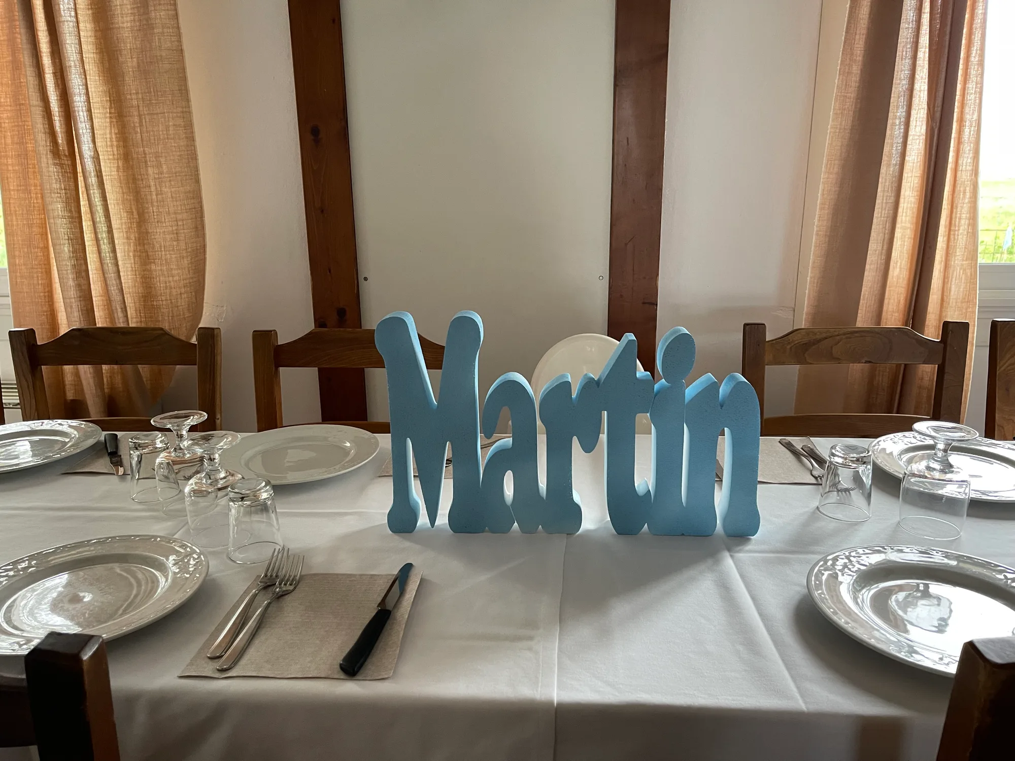 Nome Martin in lettere di polistirolo azzurre al centro di una tavola apparecchiata