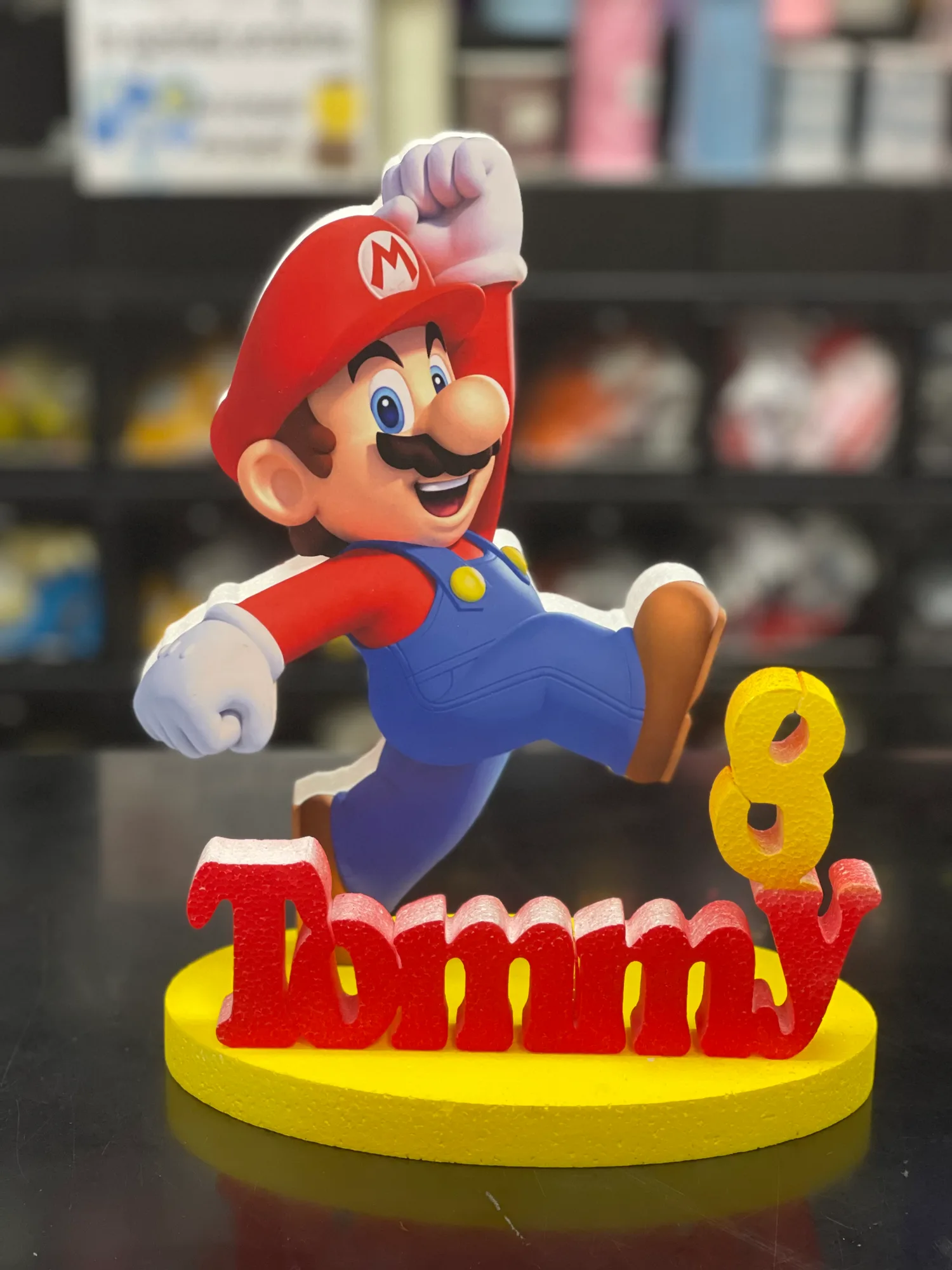 Sagoma stampata di un personaggio dei videogiochi che salta, con il nome Tommy in lettere rosse e il numero 8 giallo su una base gialla