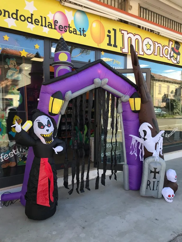 Portale gonfiabile di Halloween viola con lanterne, fantasmi, lapide e la sagoma della morte, davanti alla vetrina del negozio