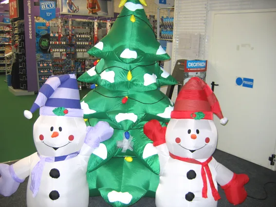 Due pupazzi di neve gonfiabili con sciarpa e cappello ai lati di un albero di Natale gonfiabile