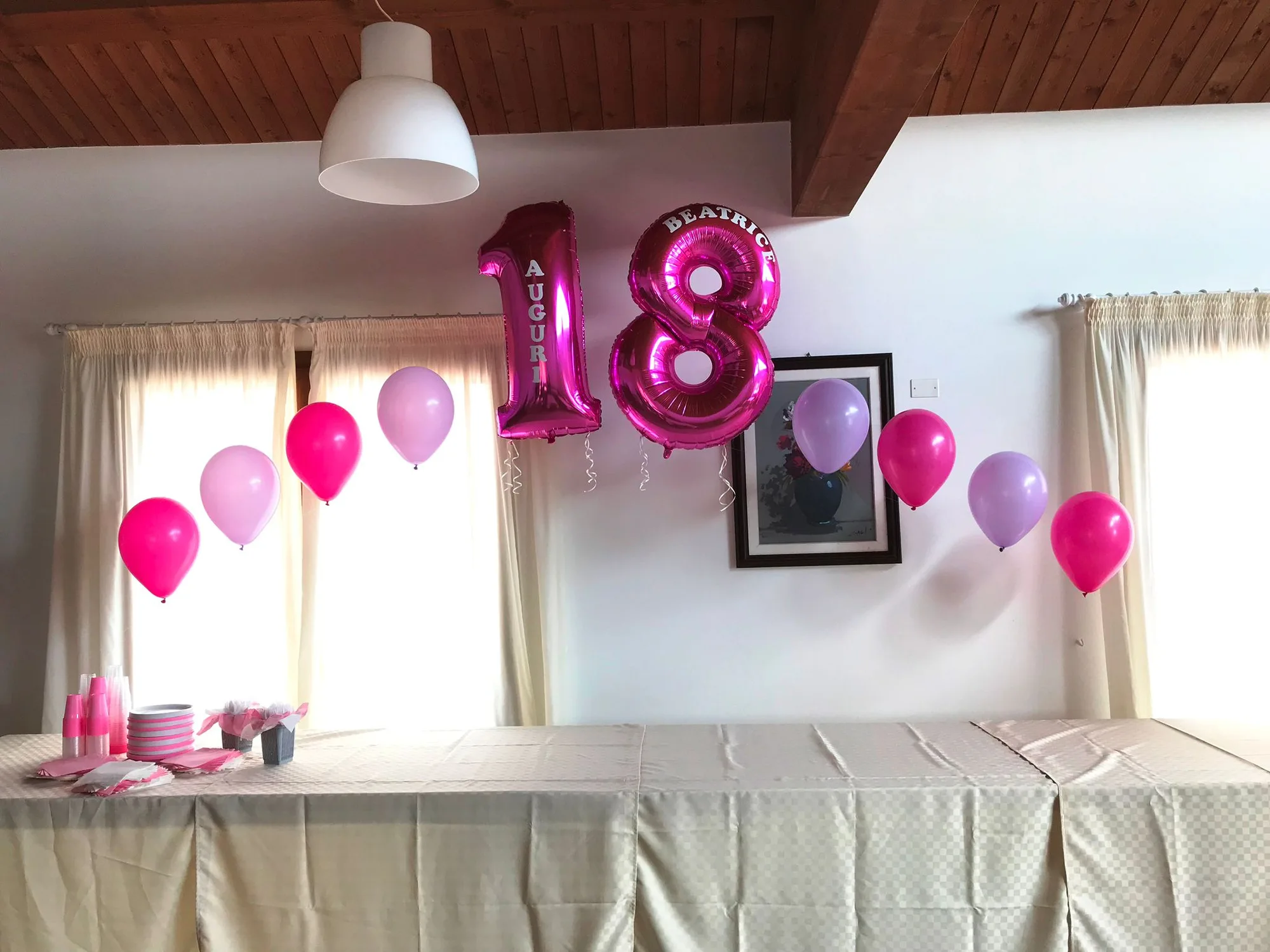 Numeri 18 giganti in mylar fucsia stampati Auguri Beatrice sospesi sopra il tavolo del buffet, con palloncini rosa e lilla a elio lungo la parete