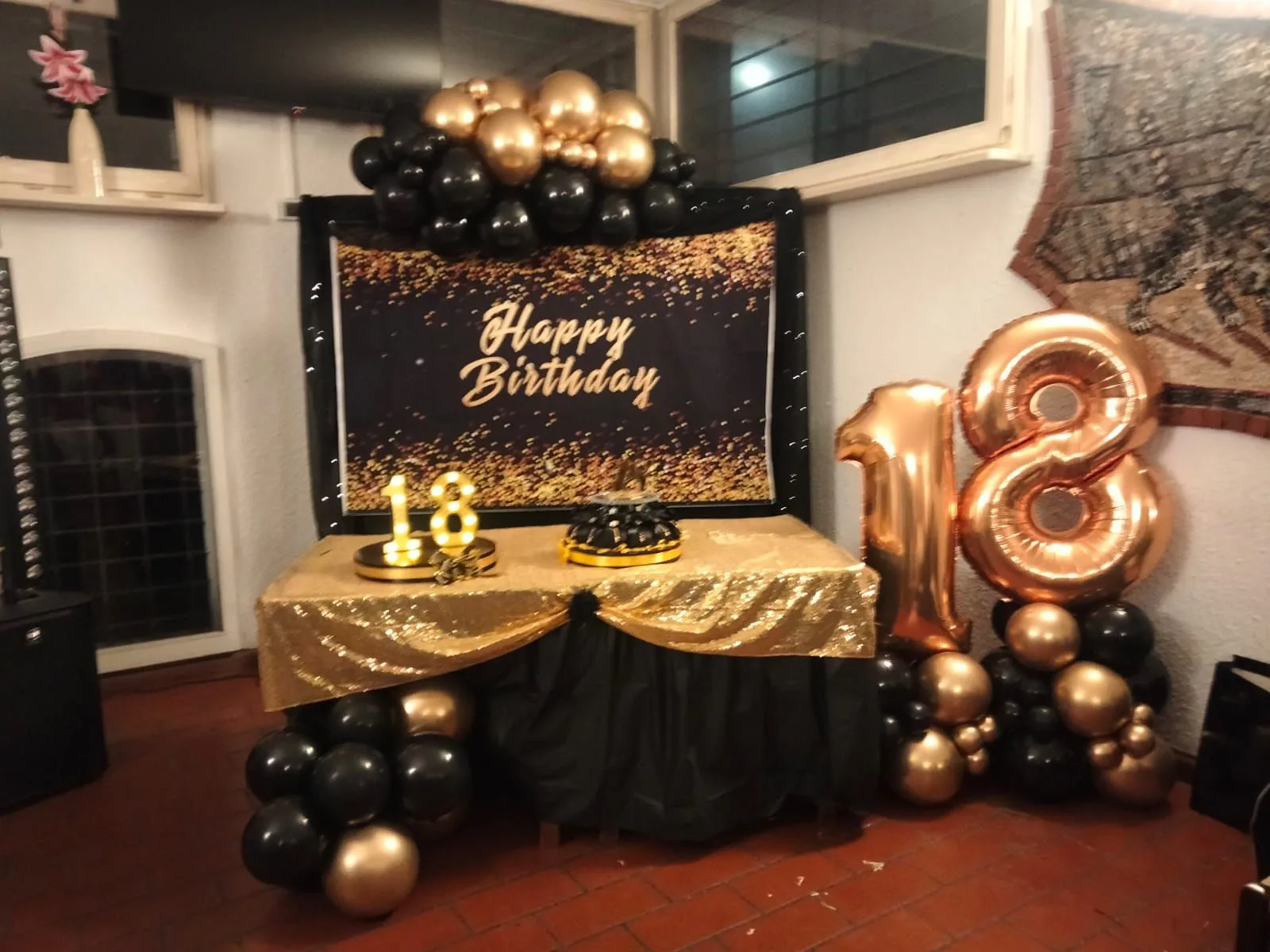 Tavolo della torta con telo Happy Birthday nero e oro, drappo dorato, scritta 18 luminosa e numero 18 in mylar oro rosa a lato