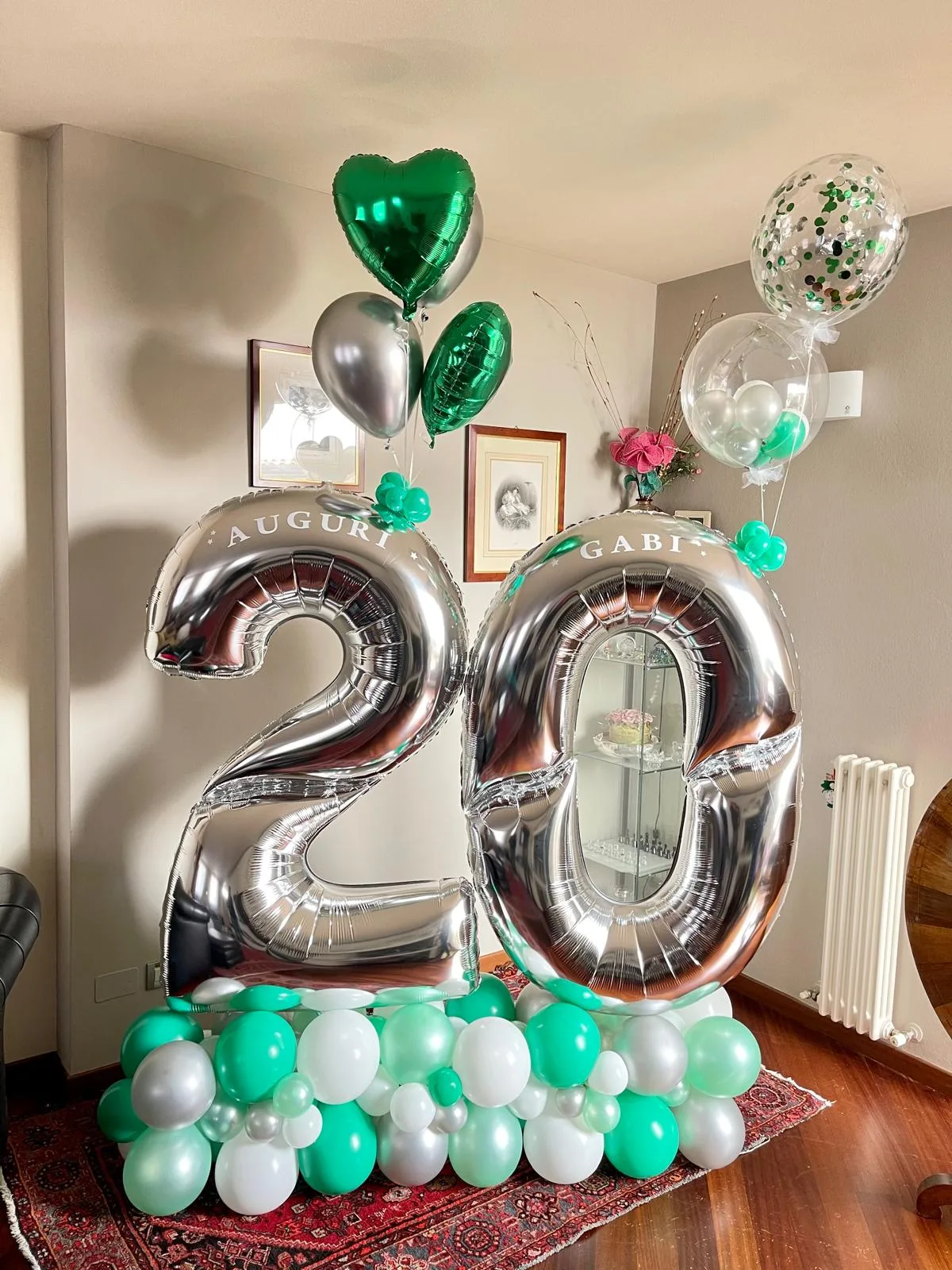 Numeri 20 giganti in mylar argento con la scritta Auguri Gabi, su una base di palloncini verde menta, bianchi e argento