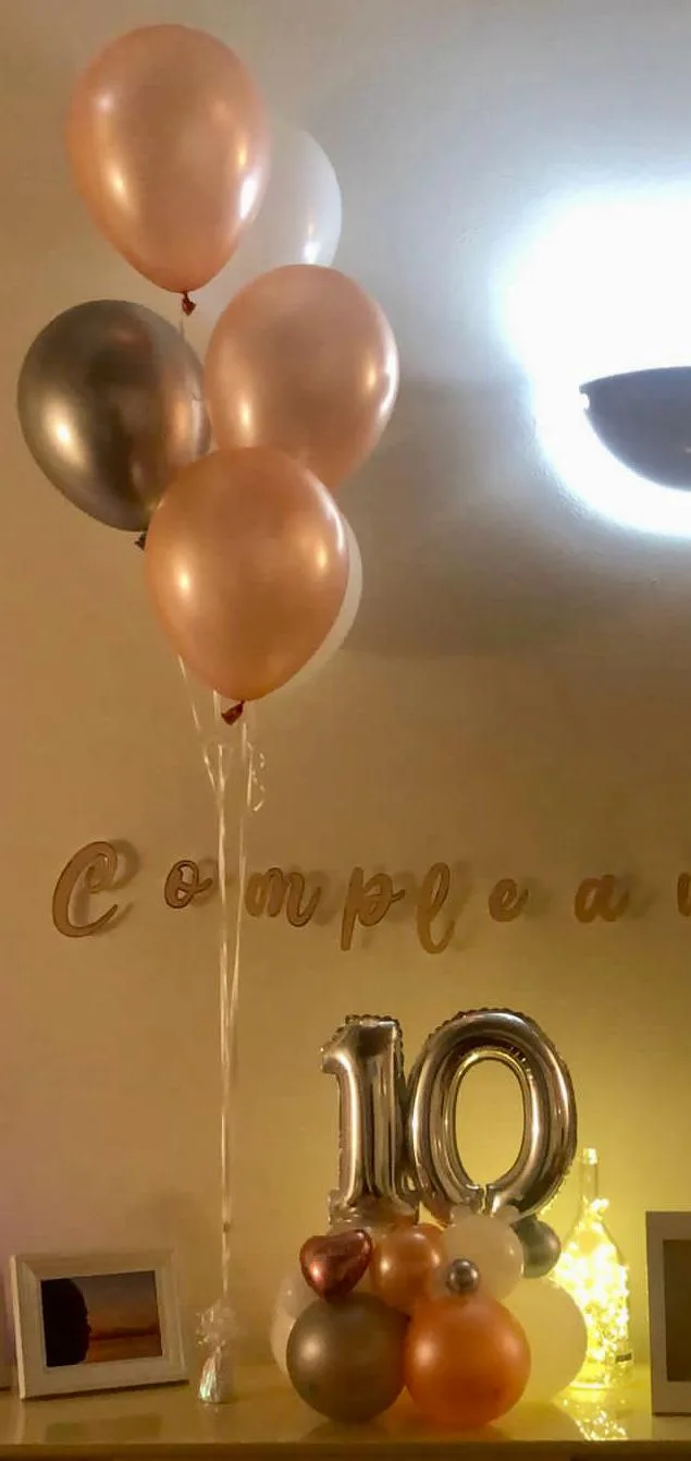Mazzo di palloncini a elio rose gold e argento sopra una mensola con il numero 10 in mylar argento e la scritta Compleanno
