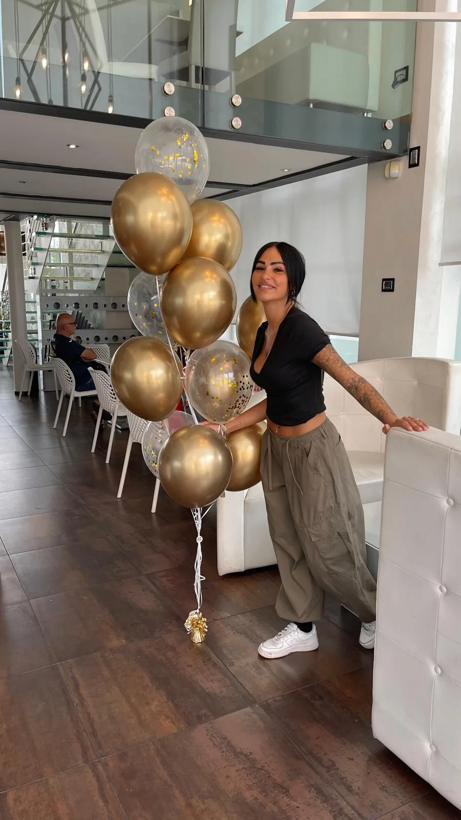 Ragazza con un mazzo di dieci palloncini a elio oro cromati e trasparenti con coriandoli, nella hall di un hotel