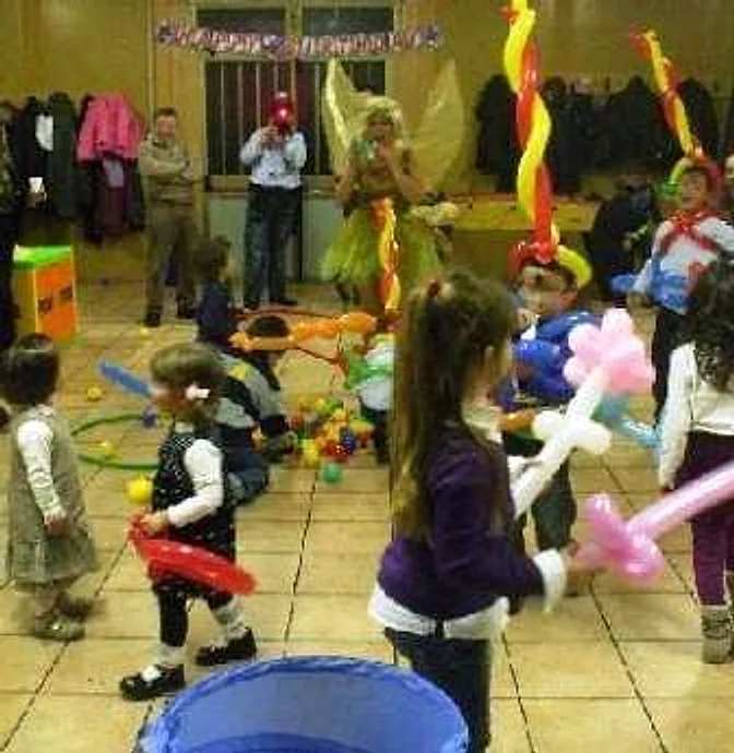 Bambini in sala con spade, fiori e animaletti di palloncini modellati durante la festa